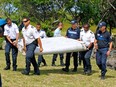 French police on Reunion Island carry a wing flap from Malaysia Flight 370 after it was recovered from the Indian Ocean on July 29, 2015.