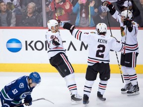 Chicago Blackhawks' Marian Hossa, left,  celebrates his game-winning goal in overtime with teammates Duncan Keith and Ryan Hartman in front of the Canucks' Bo Horvat during their game in Vancouver on Saturday night.