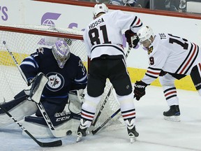 Chicago's Jonathan Toews attempts the wraparound on Jets goaltender Connor Hellebuyck as the Blackhawks' Marian Hossa looks for the rebound during first period NHL action in Winnipeg on Tuesday night.