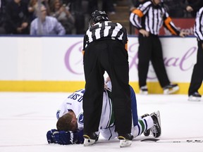 Referee Kelly Sutherland (11) checks on Vancouver Canucks left winger Daniel Sedin on Nov. 5.