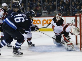 Winnipeg Jets' Blake Wheeler scores on New Jersey Devils goaltender Cory Schneider as John Moore defends during second period in Winnipeg on Tuesday. The Jets won 3-2.