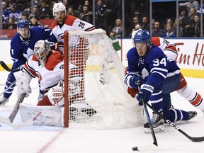 Auston Matthews of the Maple Leafs battles with the Hurricanes' Jay McClement as Csrolina goalie Cam Ward looks on during second period NHL action in Toronto on Tuesday night.