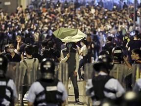 A protester holds a yellow umbrella in front of police officers after clashing as thousands of people march in a Hong Kong street, Sunday, Nov. 6, 2016.