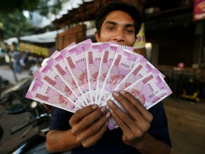 An Indian man displays new currency notes of 2000 Indian rupee in Ahmadabad, India, Friday, Nov. 11, 2016.