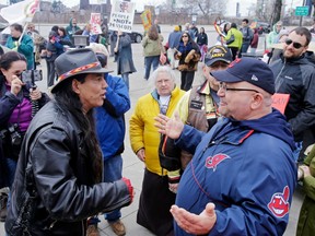 In this April 10, 2015 file photo, Philip Yenyo (left), executive director of the American Indian Movement of Ohio, talks with a Cleveland baseball fan before a home game against the Detroit Tigers. Cleveland's Chief Wahoo logo is seen on the fan's jacket sleeve.