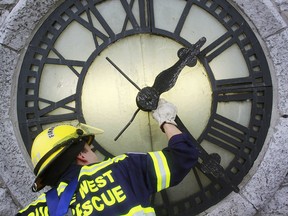 Quinte West, Ont. firefighter Basil Wood adjusts the clock tower hands on Trenton's historic town hall clock.