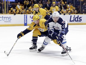 Nikolaj Ehlers of the Winnipeg Jets reaches for the puck as he is defended by the Predators' Matt Irwin  during the first period of their game Friday night in Nashville, Tenn.