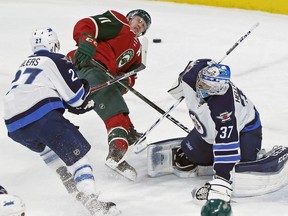 Minnesota Wild forward Zach Parise, centre, gets a shove from Winnipeg Jets' Nikolaj Ehlers, left, as goalie Connor Hellebuyck watches during the Wild's 3-1 win Wednesday in St. Paul, Minn.