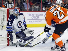 Winnipeg Jets goalie Connor Hellebuyck defends his net as the Flyers' Nick Cousins attacks during the second period of their game, Thursday night in Philadelphia.