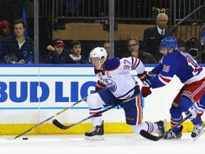 Connor McDavid, left, of the Edmonton Oilers fights off the check of New York Rangers' Jesper Fast during Thursday NHL action in New York.