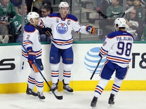 Connor McDavid (centre) celebrates with Edmonton Oilers teammates Andrej Sekera (left) and Jesse Puljujarvi after scoring against the Dallas Stars on Nov. 19.