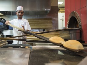 Ehssan Harba pulls pitas out of the oven at Paramount Fine Foods in Mississauga, Ont.
