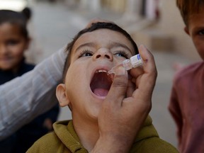 Pakistani child Sajjad (C) who was displaced with his family by fighting during Pakistan Army operations against the Taliban in the country's tribal belt which borders Afghanistan receives polio vaccination drops from health worker Mohammad Amjad (L, partially seen) in Rawalpindi on April 8, 2014.