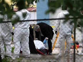 Officers and detectives watch as the body of Amir Hayat Malik is removed from an alley behind the 500 block of Brant Street on June 4, 2015