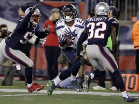 Seattle Seahawks running back C.J. Prosise catches a pass between New England Patriots defenders Elandon Roberts, left, and Devin McCourty during the second half on Sunday in Foxborough, Mass. The Seahawks prevailed 31-24.