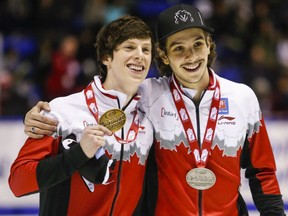 Canadian speedskaters Charle Cournoyer, left, and Samuel Girard hold up their medals after earning gold and silver respectively in the 1,000m event at the World Cup short track speedskating championships at the Olympic Oval in Calgary.