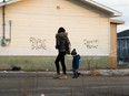 A young woman and a child walk along a street in Attawapiskat on the day Indigenous Affairs Minister Carolyn Bennett visited in April.