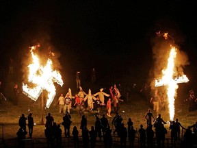 In this Saturday, April 23, 2016 photo, members of the Ku Klux Klan participate in cross and swastika burnings after a "white pride" rally in rural Paulding County near Cedar Town, Ga