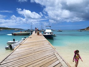 A child wades through the water along the pier at Road Bay in Sandy Ground on the Caribbean island of Anguilla. The pier is popular with visitors who take shuttle boats out to nearby Sandy Island for lunch and a day of snorkelling.
