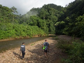 Caves Branch guides Alex Guzman and Rosa Montero walking along the Caves Branch River in Belmopan, Belize, to a point where it disappears into a cavern. As part of the resort's Overnight Jungle Adventure, adventurers can swim into this cavern.