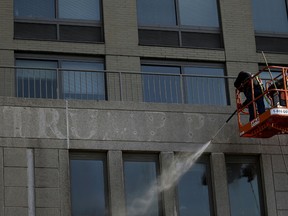 A workman power sprays the outline of the word "Trump" off a residential building in New York. Donald Trump's name is being stripped off three luxury apartment buildings after hundreds of tenants signed a petition saying they were embarrassed to live in a place associated with the Republican president-elect.