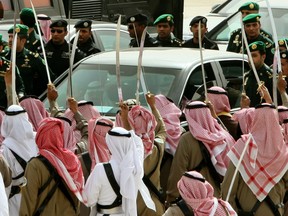 Saudi guard of honour raise their swords as they welcome King Abdullah bin Abdul Aziz (in vehicle) upon his arrival at the Saudi capital Riyadh on February 23, 2011. The king arrived in his homeland after three months abroad, boosting social benefits for his people as he returned to a Middle East rocked by anti-regime uprisings. AFP PHOTO/HAMAD OLAYAN (Photo credit should read HAMAD OLAYAN/AFP/Getty Images)
