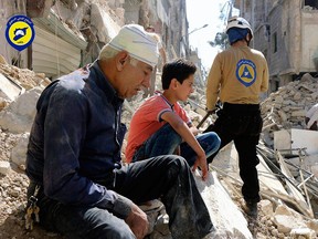 Residents sit amidst rubble in rebel-held eastern Aleppo, Syria, in this Oct. 11, 2016, photo provided by the Syrian Civil Defence group known as the White Helmets.
