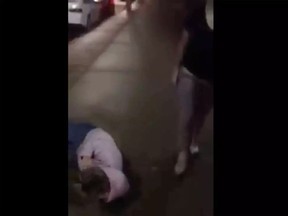 An image from a viral video showing a group of Windsor teens attacking one female teen, who cowers against a wall while the suspects bully her