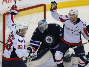 Jets goalie Connor Hellebuyck looks down as Washington Capitals' Jay Beagle, left, celebrates his game winning goal with Evgeny Kuznetsov in Winnipeg on Tuesday night. The Capitals won 3-2.