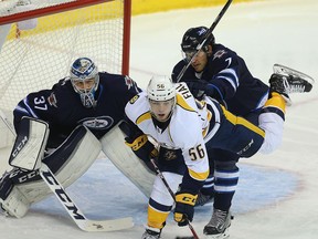 Winnipeg Jets goaltender Connor Hellebuyck (left) watches play behind defenceman Ben Chiarot (right) and Nashville Predators winger Kevin Fiala on Nov. 27.