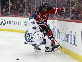 New Jersey Devils forward Taylor Hall (right) hits Vancouver Canucks defenceman Philip Larsen on Dec. 6.