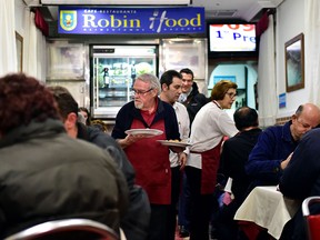 Waiters clear plates and serve dishes during a free dinner at the Robin Hood restaurant in Madrid on December 1, 2016.