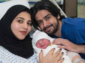 A handout picture released on December 15, 2016 shows Moaza Al Matrooshi posing with her husband Ahmed and their newly born son at a hospital in London on December 14, 2016.