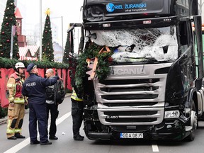 A policeman and fire fighters stand next to the truck at the scene where it crashed into a Christmas market near the Kaiser Wilhelm Memorial Church in Berlin.
