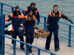 Russian rescuers carry a stretcher with a body recovered after a Russian military plane crashed in the Black Sea, on a pier outside Sochi, on December 25.