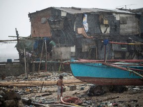 A boy runs for cover as it rains near the breakwater in Baseco, Manila on December 26, 2016