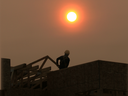A construction worker in Bridgeland is silhouetted by the smoke shrouded sun at about 8:30 on Tuesday morning.