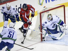 Washington Capitals right wing T.J. Oshie tries to get past Vancouver Canucks centre Henrik Sedin,, defenseman Troy Stecher as Vancouver Canucks goalie Jacob Markstrom watches during the third period Sunday in Washington. The Capitals won 3-0.