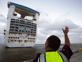 In this Nov. 5, 2013 photo, Caribbean Princess cruise ship officer waves as the cruise ship Caribbean Princess leaves from the Bayport Cruise Terminal in Pasadena, Texas.
