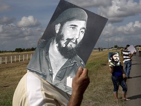 A man uses a picture of Fidel Castro as cover from the sun while waiting for the convoy carrying the ashes of Cuban leader Fidel Castro along the central road near Yarigua, Las Tunas province, Cuba, Friday, Dec. 2, 2016.