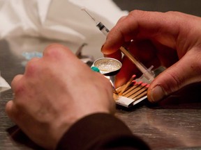 A man prepares heroin he bought on the street to be injected at the Insite safe injection clinic in Vancouver, B.C.