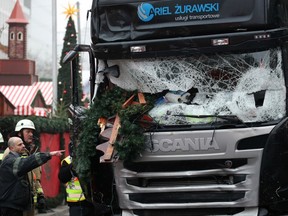 Firefighters stand next to a damaged truck in Berlin, Germany, Tuesday Dec. 20, 2016.