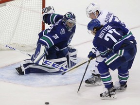 Canucks goaltender Ryan Miller makes a save against Toronto Maple Leafs' Jake Gardiner as Ben Hutton defends during overtime action in Vancouver on Saturday night.