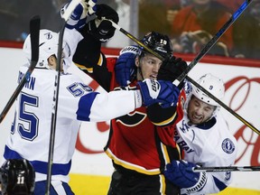 Tampa Bay Lightning's Tyler Johnson, right, and Braydon Coburn check the Flames' Matthew Tkachuk during the second period of their game in Calgary on Wednesday night.