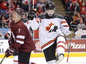 Canada forward Taylor Raddysh celebrates his fourth goal of the game as Latvia defenceman Maksims Ponomarenko looks on during third-period action at the world junior hockey championship in Toronto on Thursday night.