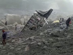In this photo made from video, people watch an excavator dig into a collapsed mine, Friday, Dec. 30, 2016