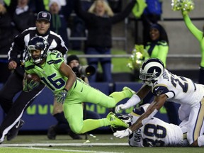 Tyler Lockett of the Seattle Seahawks hauls in a touchdown pass from Russell Wilson as two Los Angeles Rams defenders can only watch during the Thursday night NFL game in Seattle. The Seahawks clinched their third NFC West title in four seasons with a decisive 24-3 win over the hapless Rams.
