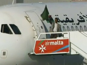 An unidentified man believed to be the hijacker of an Afriqiyah Airways flight waves a flag as he surrenders at Malta International airport as  Friday, Dec. 23, 2016.