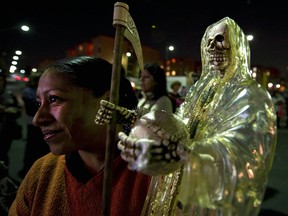 A devotee of the 'Santa Muerte' holds a image as she prays at the shrine of the goddess at the Iztapalapa shantytown in Mexico City, on February 4, 2011