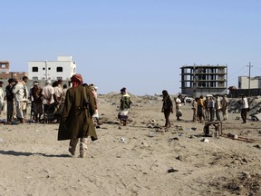 Soldiers and people gather at the site of a suicide bomb at a base in the southern city of Aden, Yemen, Sunday, Dec. 18, 2016.
